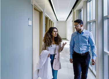 Two students walking and talking in a hallway.